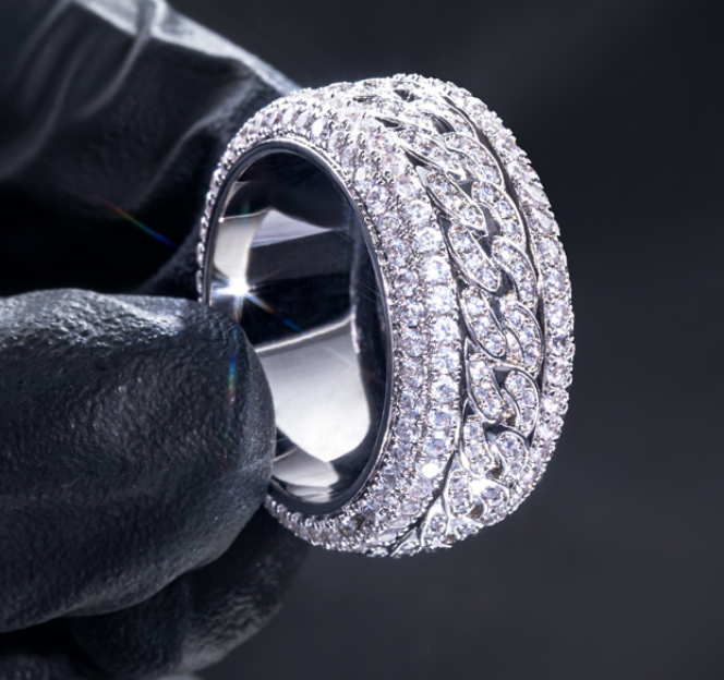 Close-up of a diamond ring held by black gloves against a dark background
